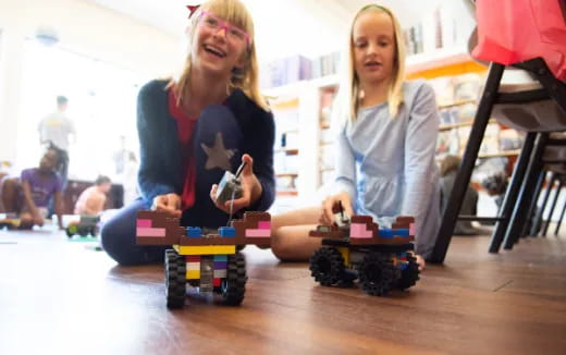a couple of girls playing with toy cars