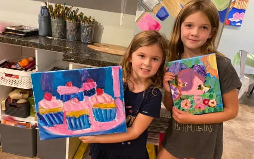 a couple of girls holding a cake