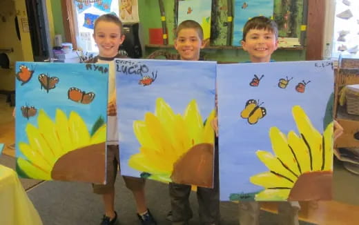 a group of children holding up paintings