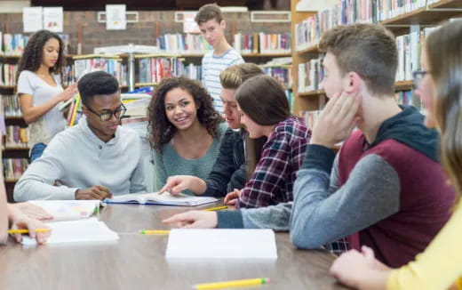 a group of people sitting at a table in a library