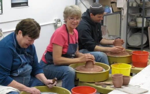 a group of people working on clay pots