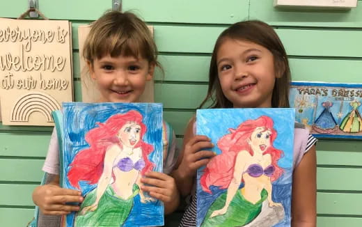 a couple of children holding paintings