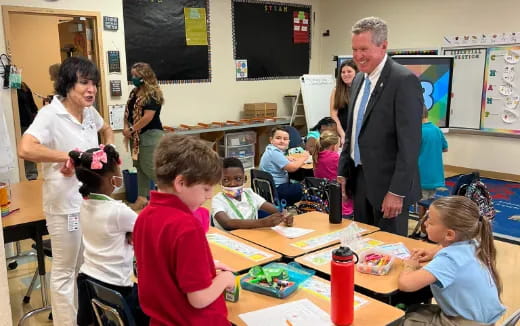 a man and a woman talking to children in a classroom
