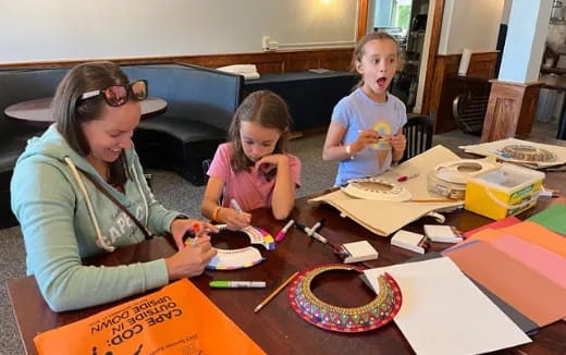 a group of children sitting at a table with art