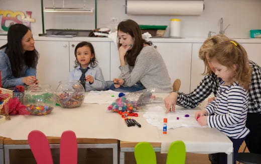 a group of children sitting at a table with toys