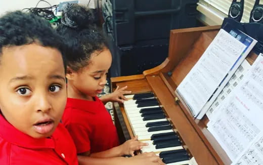 a couple of young boys playing piano