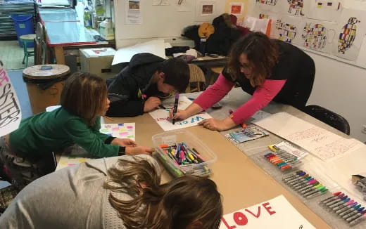 a group of people sitting at a table writing on paper