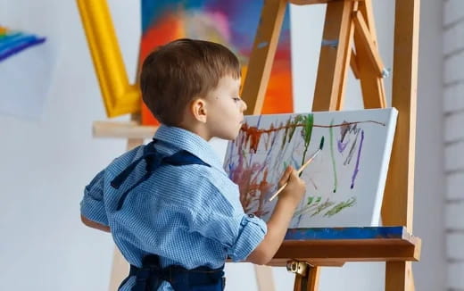 a young boy drawing on a white board