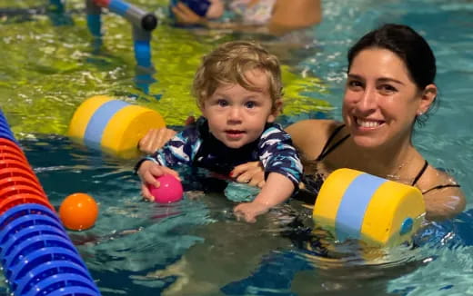 a person and a baby in a pool with balls