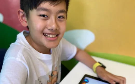 a boy smiling and holding a pen