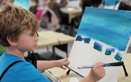 a young boy drawing on a white board