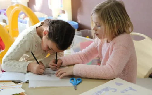 a young boy and girl writing on paper