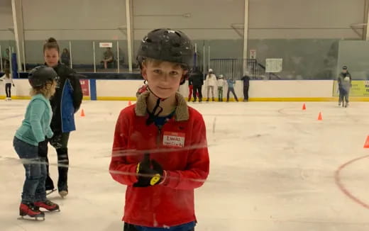 a young boy wearing a helmet and ice skates