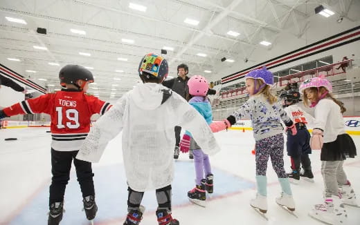 a group of kids wearing helmets and ice skates