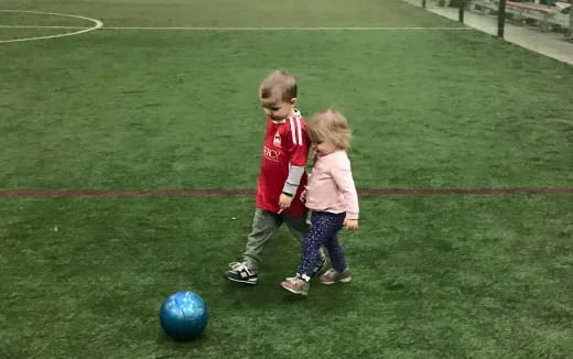 a couple of children playing with a ball on a field