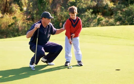 a person and a boy playing golf