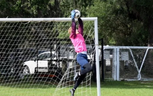 a girl jumping to catch a football ball