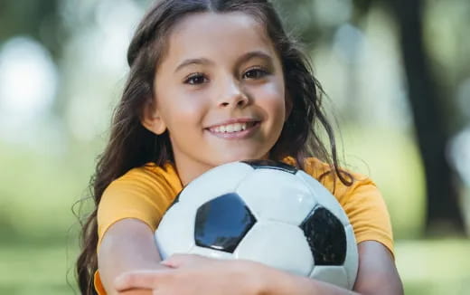 a girl holding a football ball
