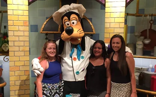 a group of women posing with a person in a garment