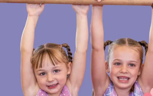a couple of girls holding onto a wooden pole