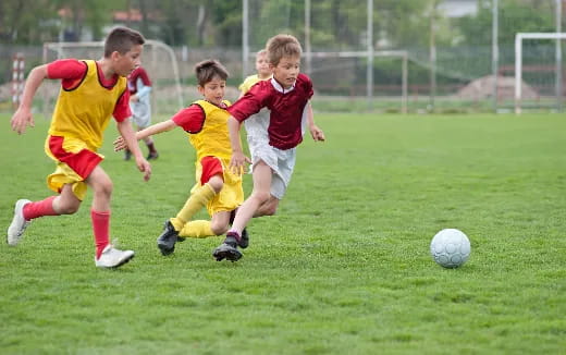 a group of kids compete over a football ball