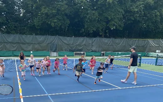 a group of kids playing tennis