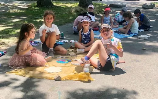 a group of people sitting on a blanket on a beach