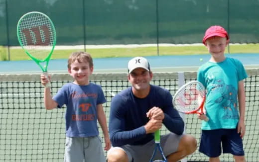 a group of kids stand on a tennis court