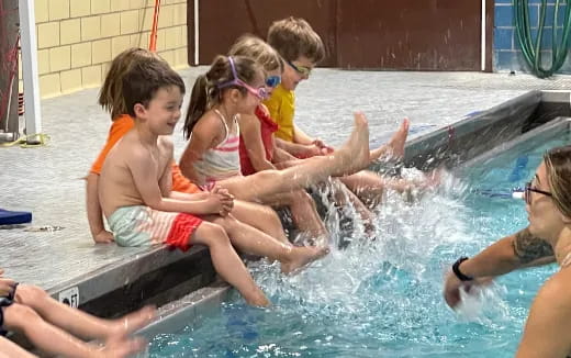 a group of children playing in a pool