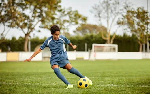 a boy kicking a football ball