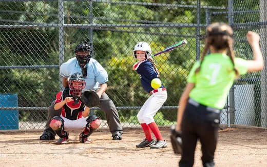 a girl hitting a ball with a baseball bat