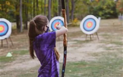 a person holding a pole with a target and arrows
