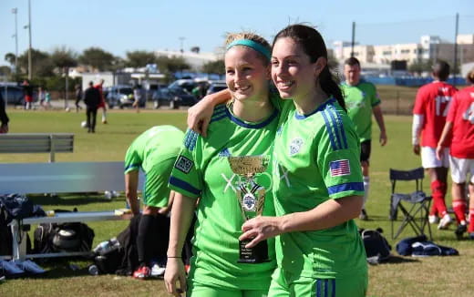 a couple of women in green uniforms holding a trophy