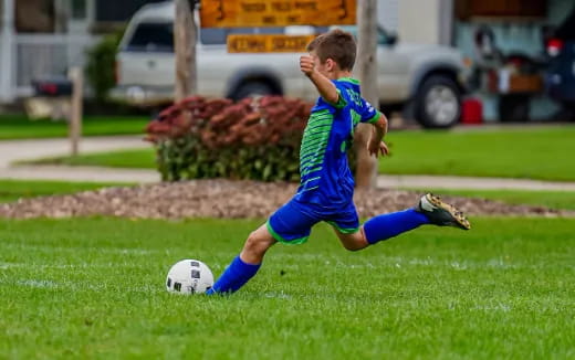 a boy kicking a football ball