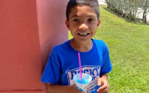 a boy smiling and holding a cup