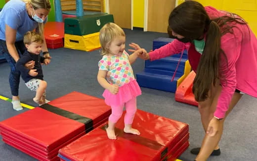 a person and children playing on a red mat