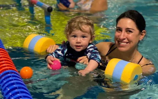 a person and a baby in a pool with balls