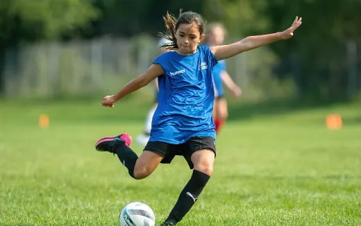 a girl kicking a football ball