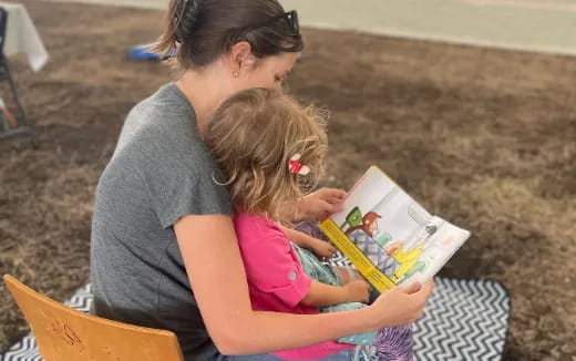 a person reading a book to a young girl