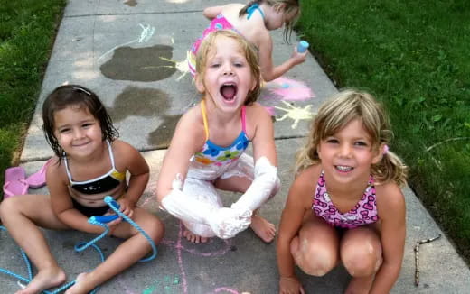 a group of girls in swimsuits sitting on a sidewalk