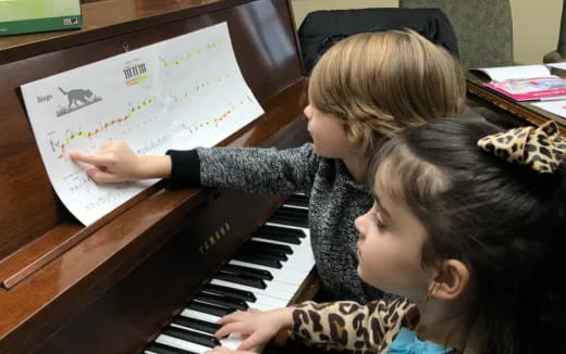 a couple of girls playing piano