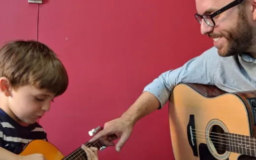 a man playing guitar with a boy