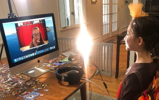a person sitting at a desk with a computer and a lamp