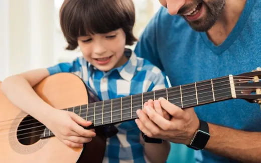 a man playing a guitar with a young boy