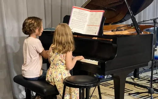 a couple of girls playing piano