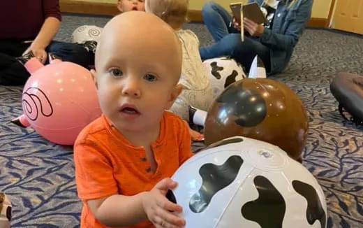 a baby with a group of balloons
