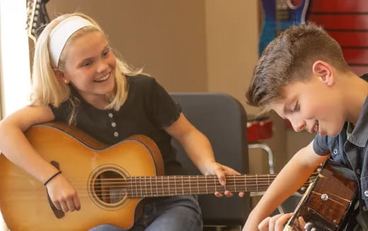 a woman playing a guitar next to a man