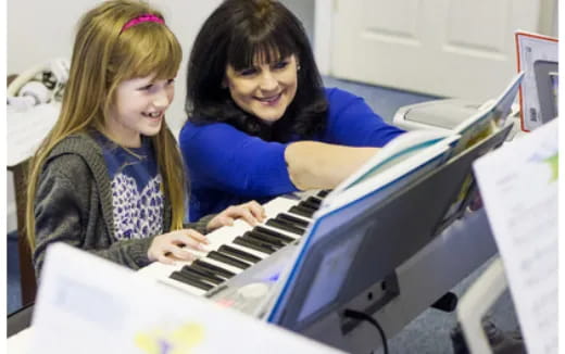a couple of girls playing a piano