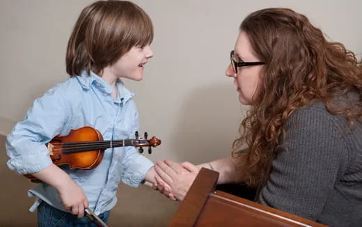 a person playing a violin to a young boy