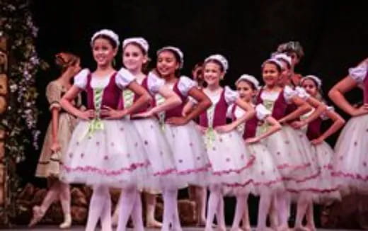 a group of girls in dresses and skirts holding sticks